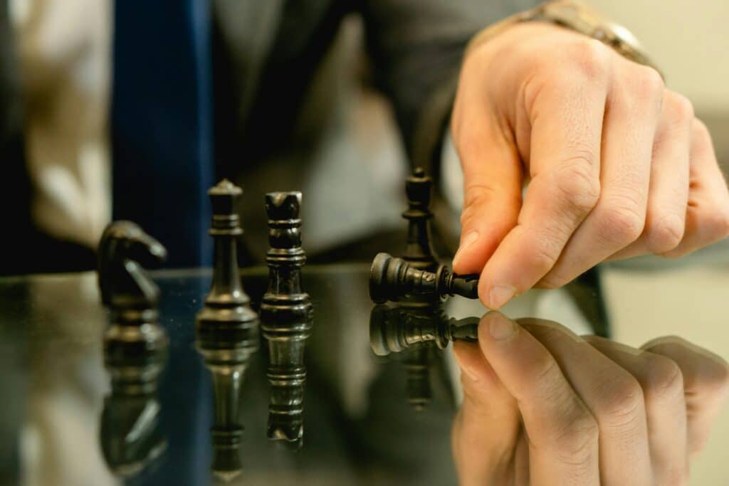 Strategia sprzedaży Challengera Hand moves chess piece in strategic game setting, reflecting planning and decision-making.